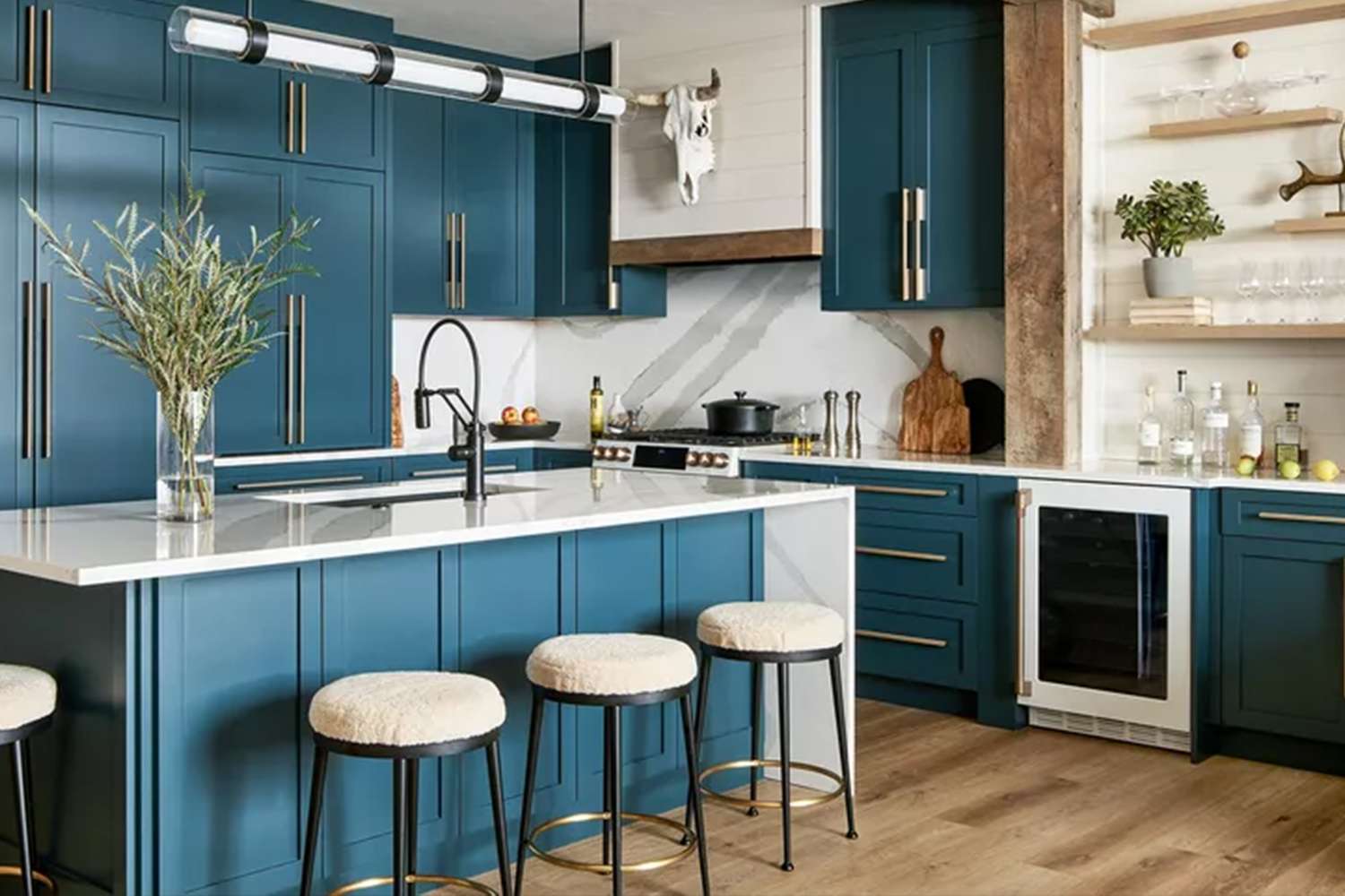 A modern kitchen with a center island bar stools and blue cabinetry