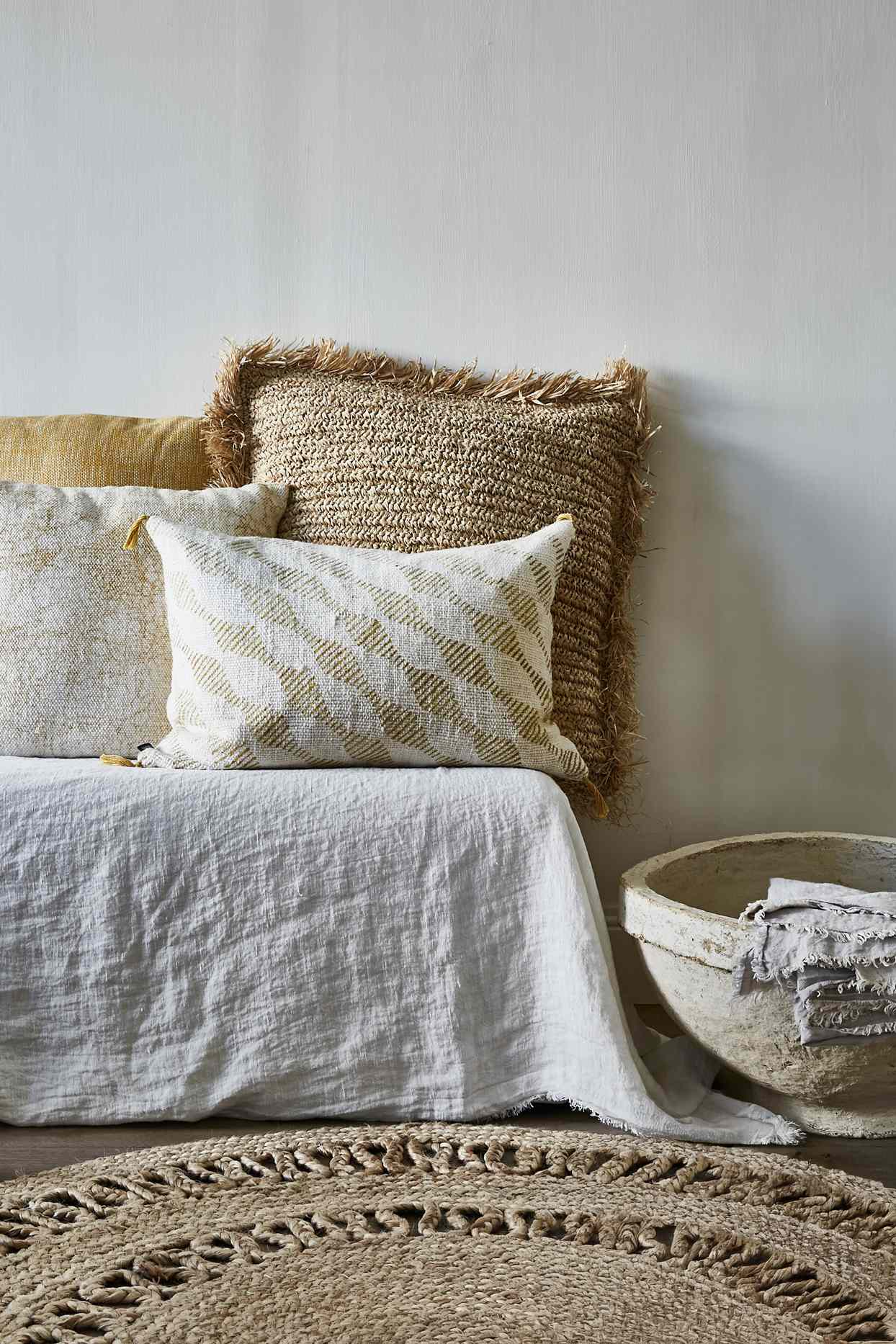 A cozy seating arrangement with pillows a woven rug and a basket