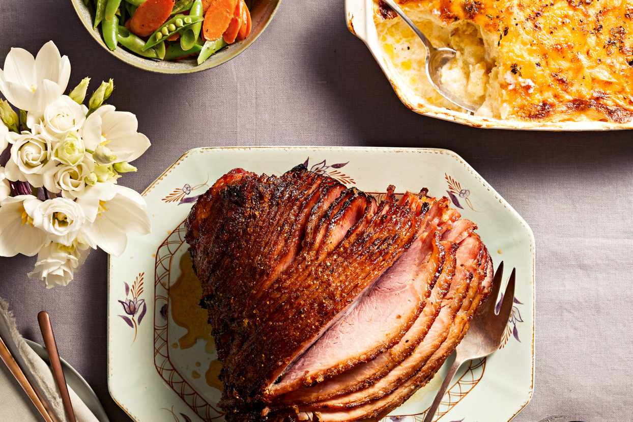 Honey-Glazed Spiral Ham next to sides of vegetables and potato dish