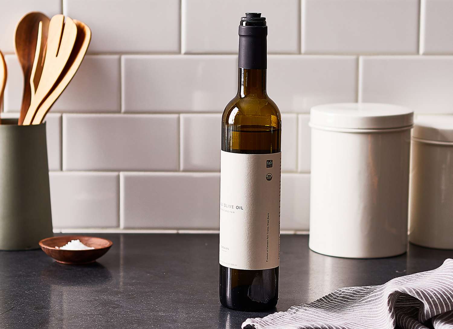 bottle of olive oil on a black countertop with white backsplash
