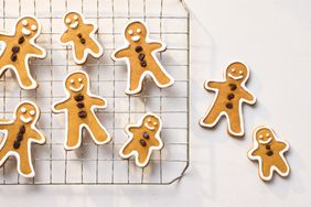 Gingerbread men cookies with icing and raisin decorations on a cooling rack
