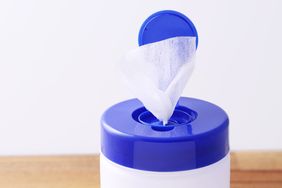 Container with disinfectant wipes lid open with a wipe partially pulled out