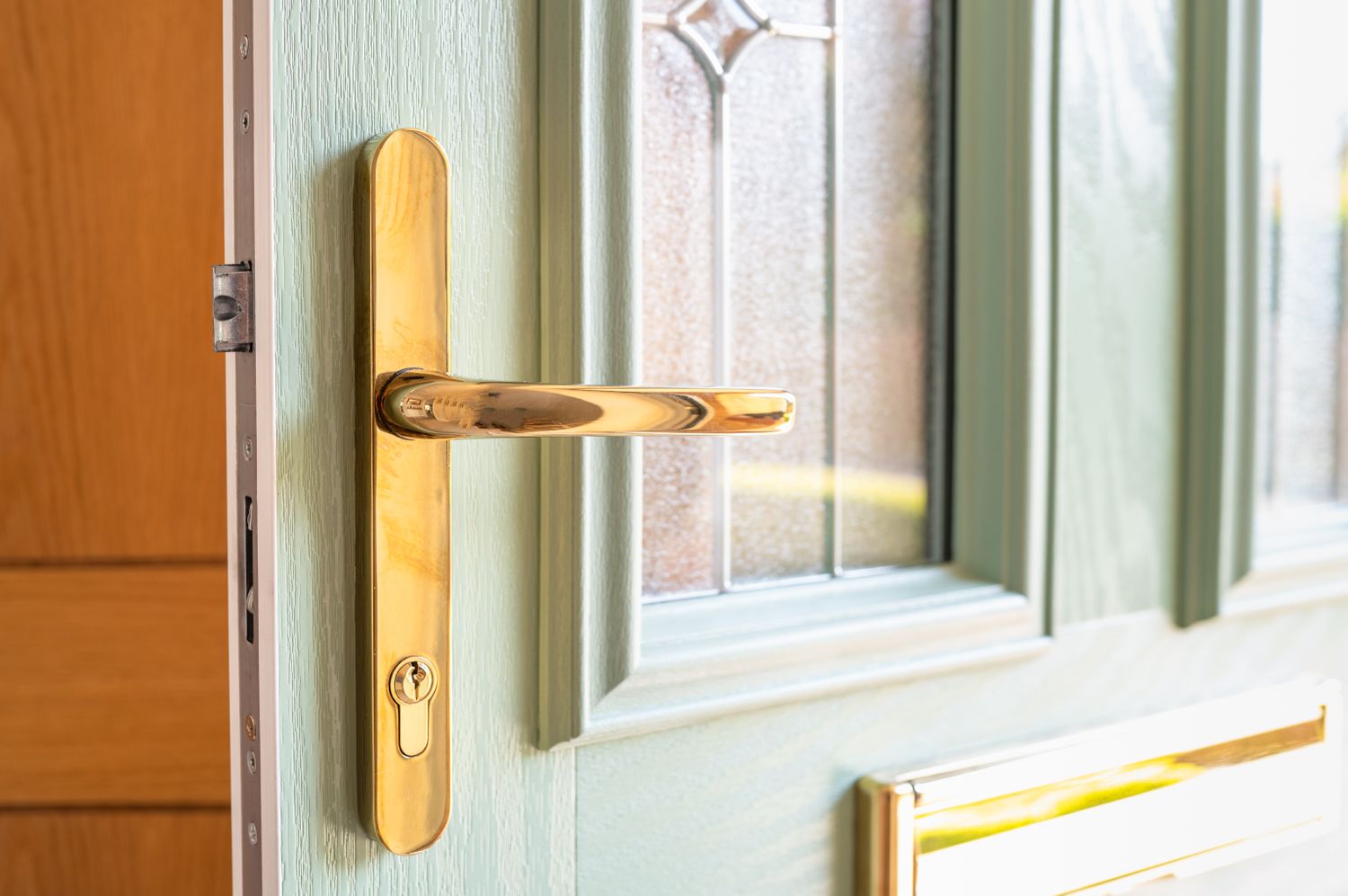 Front door with brass hardware and a decorative window inset