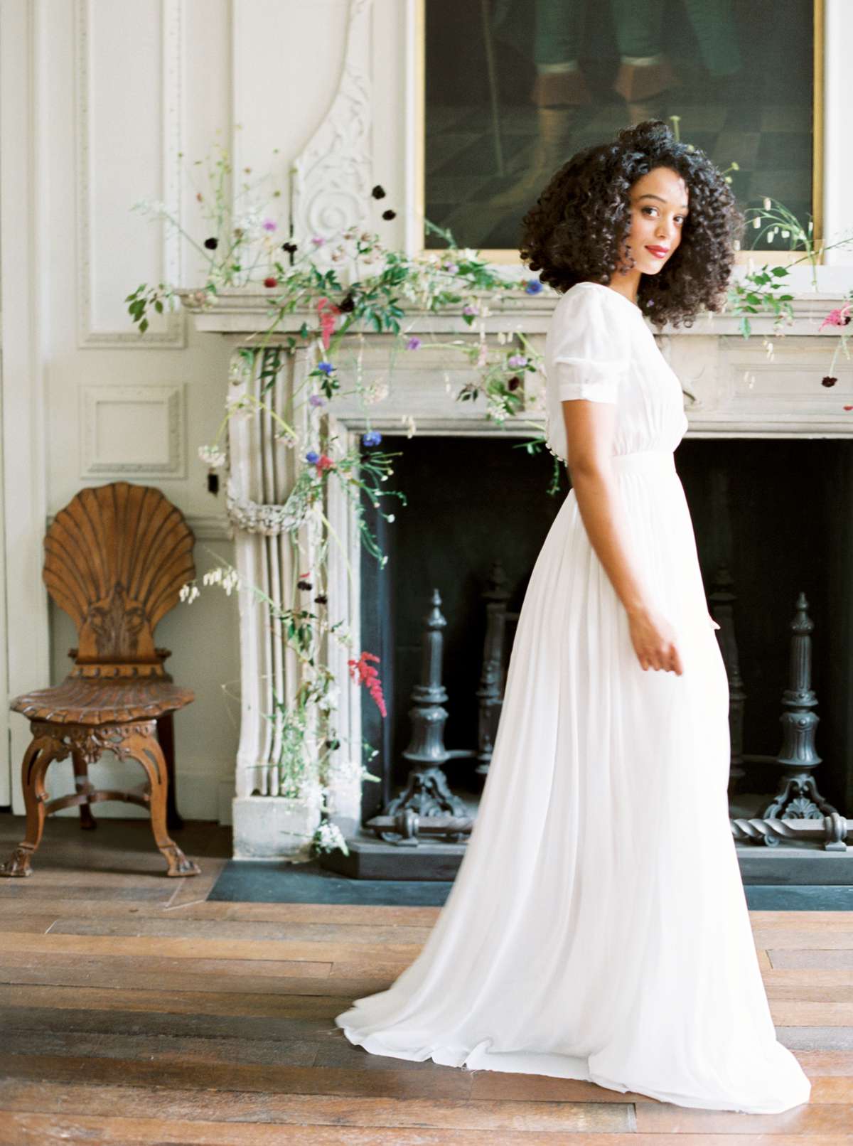 bride standing in front of white fireplace decorated with floral garland
