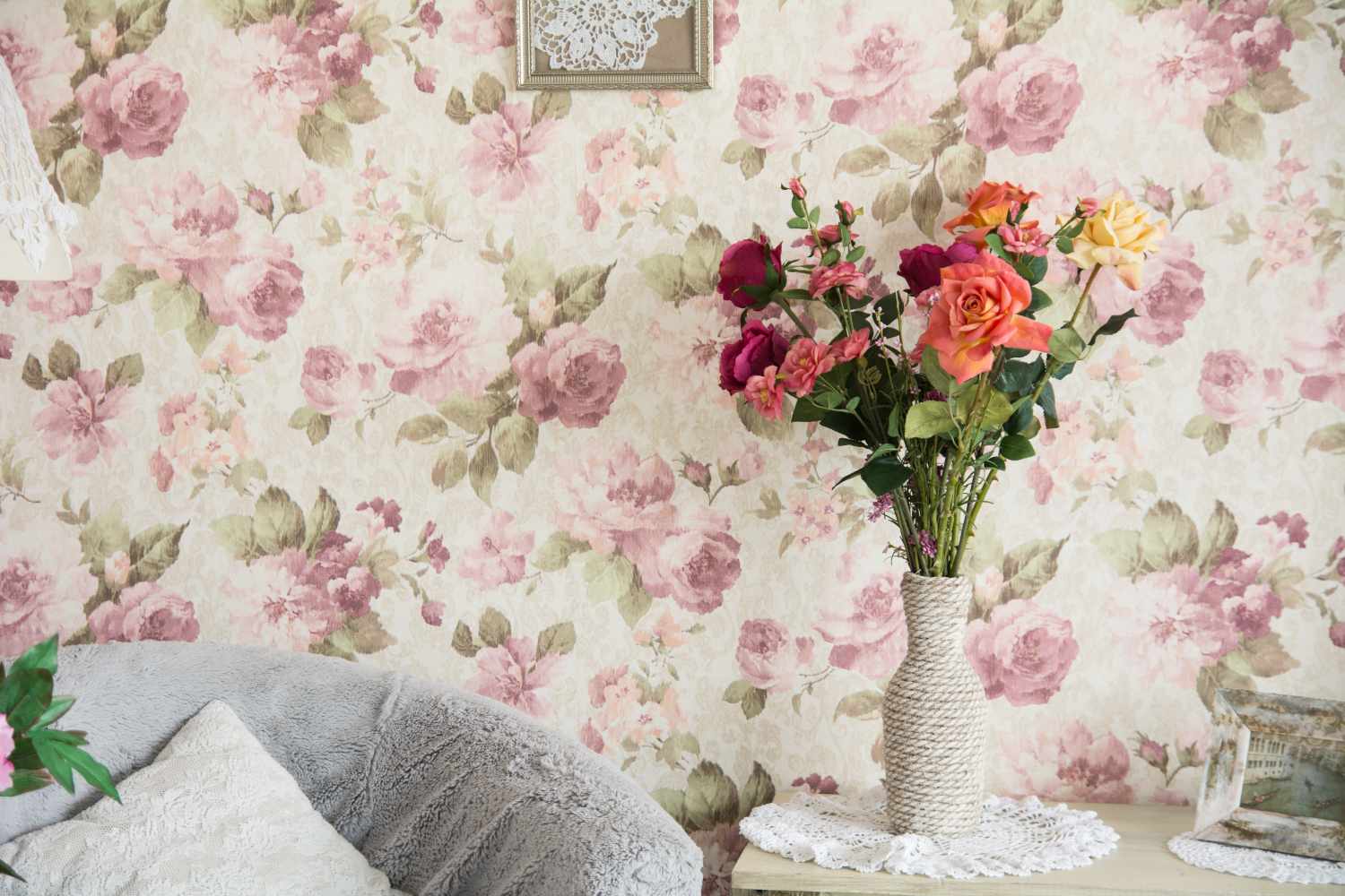 Interior room with chairs, pillowsand flowers. Room in retro style and paper wallpaper with roses