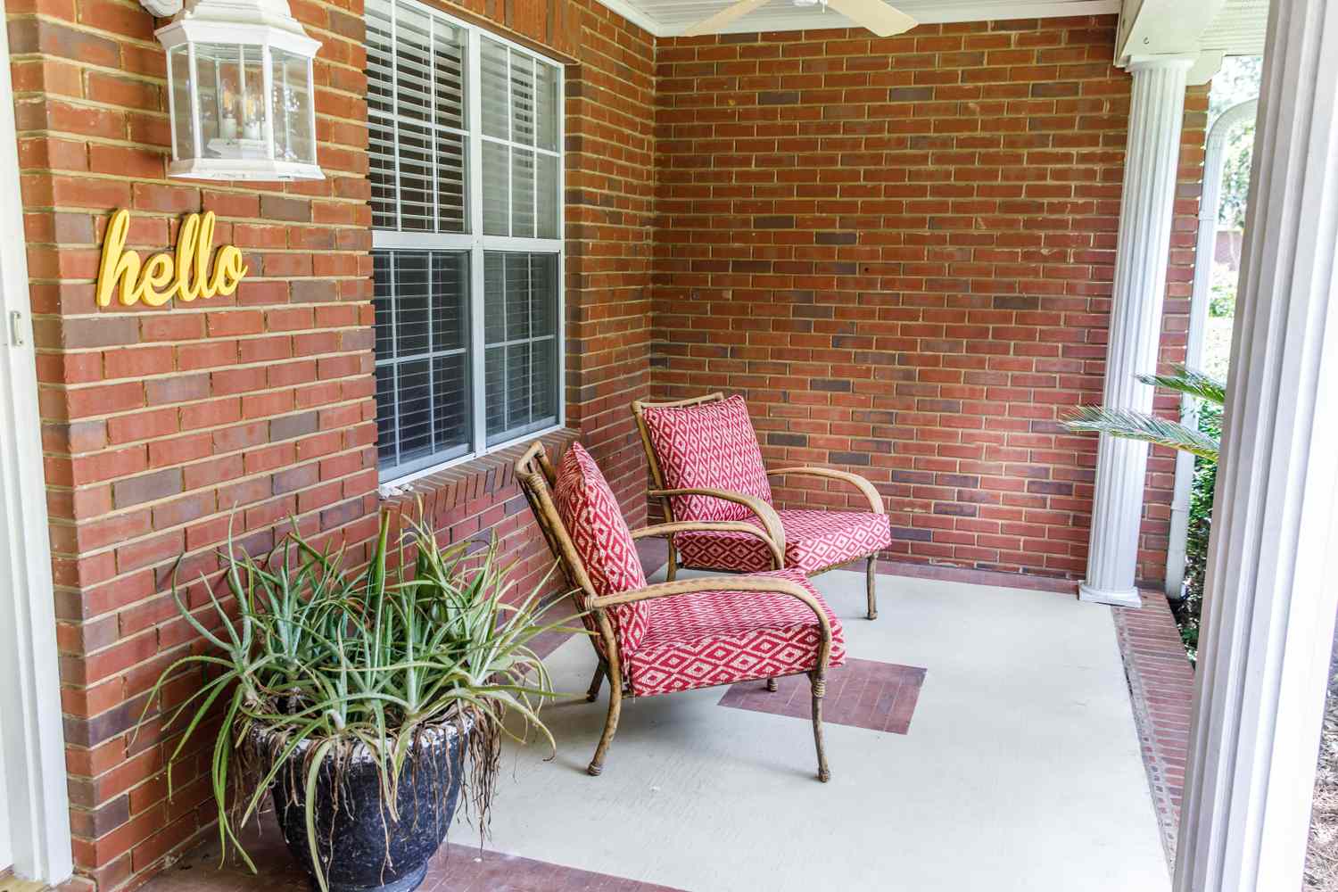 Front porch with two chairs a planter and brick walls