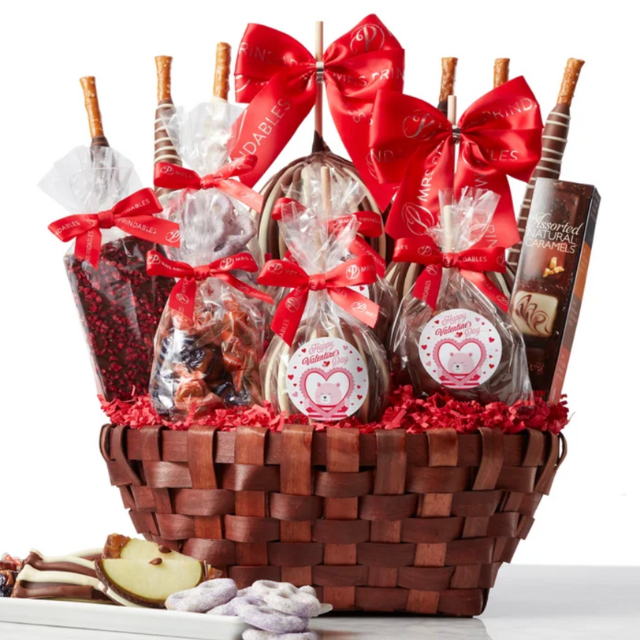 A gift basket containing chocolates snacks and treats wrapped in red ribbons
