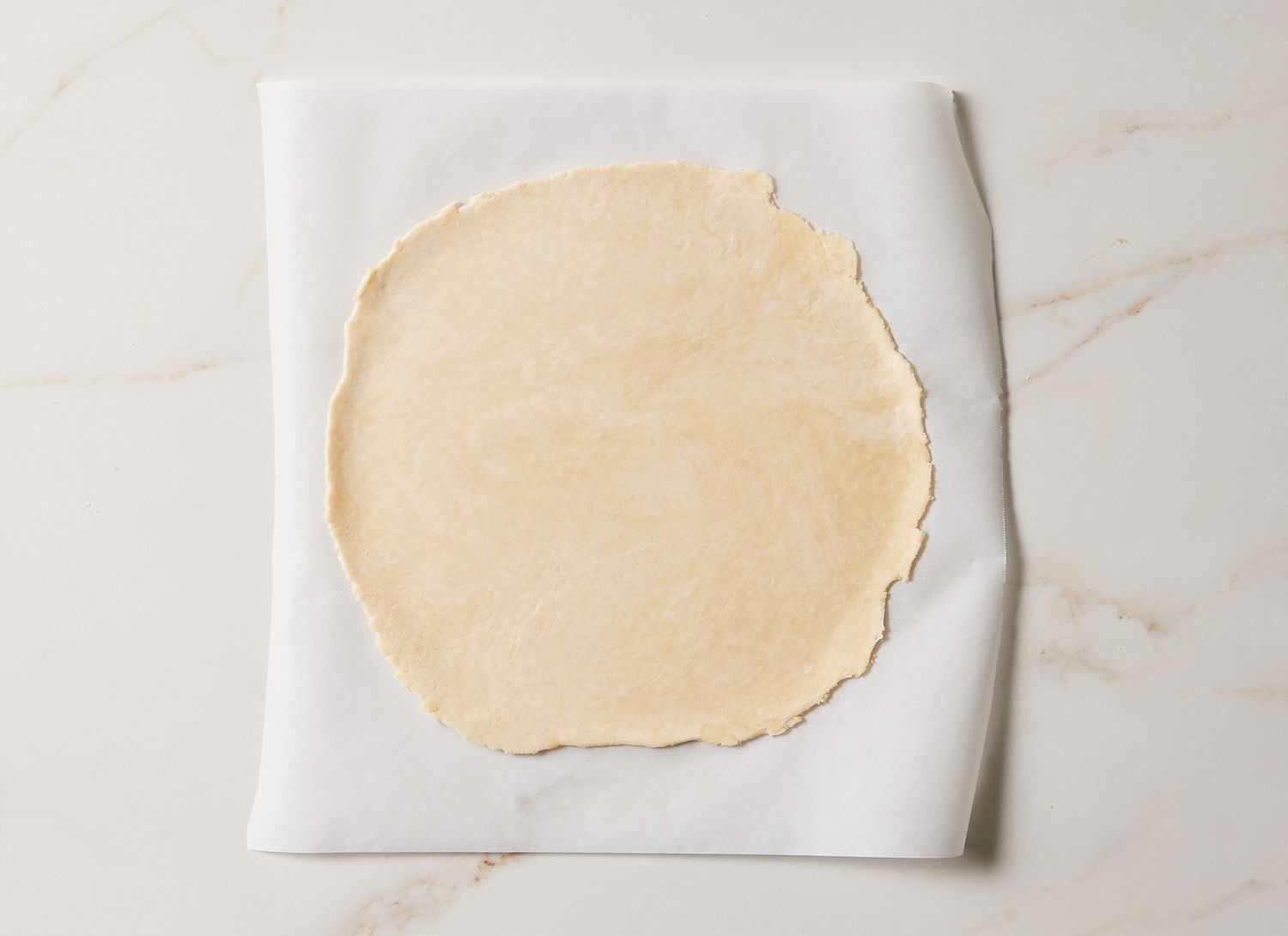 overhead view of pie dough flattened on parchment paper
