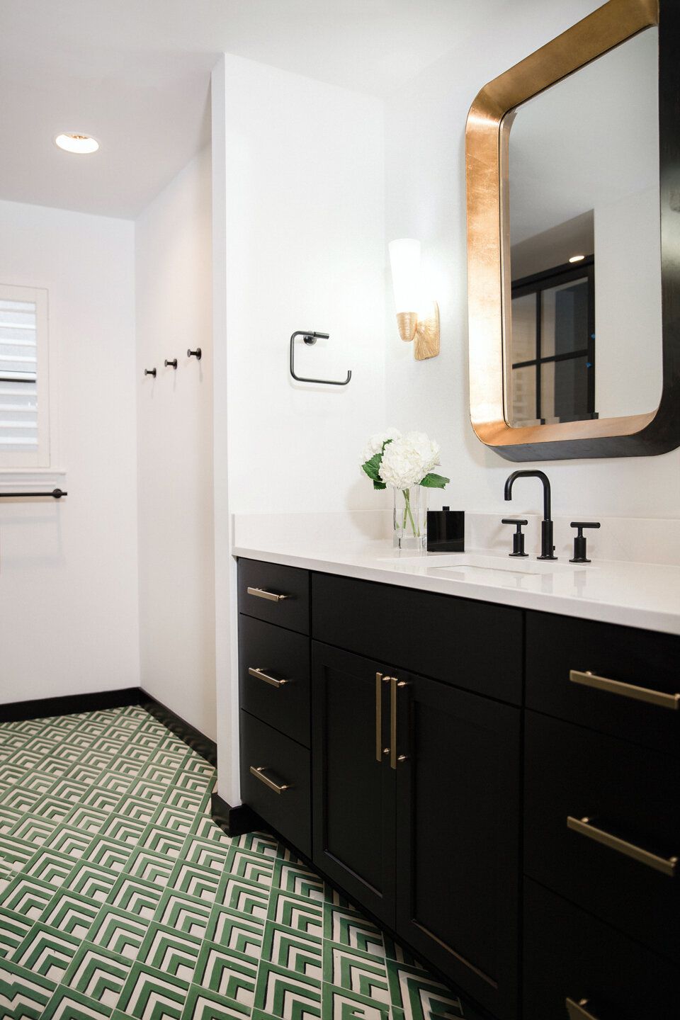 a black and white bathroom with a bold geometric green tiled floor