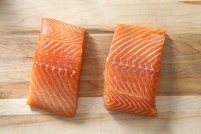 Two raw salmon fillets on a wooden surface