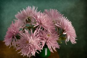 A bouquet of flowers in a green vase on a wooden table