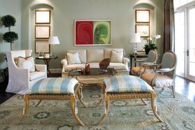 A wellfurnished living room with chairs a sofa and a patterned rug decorated with artwork on the wall