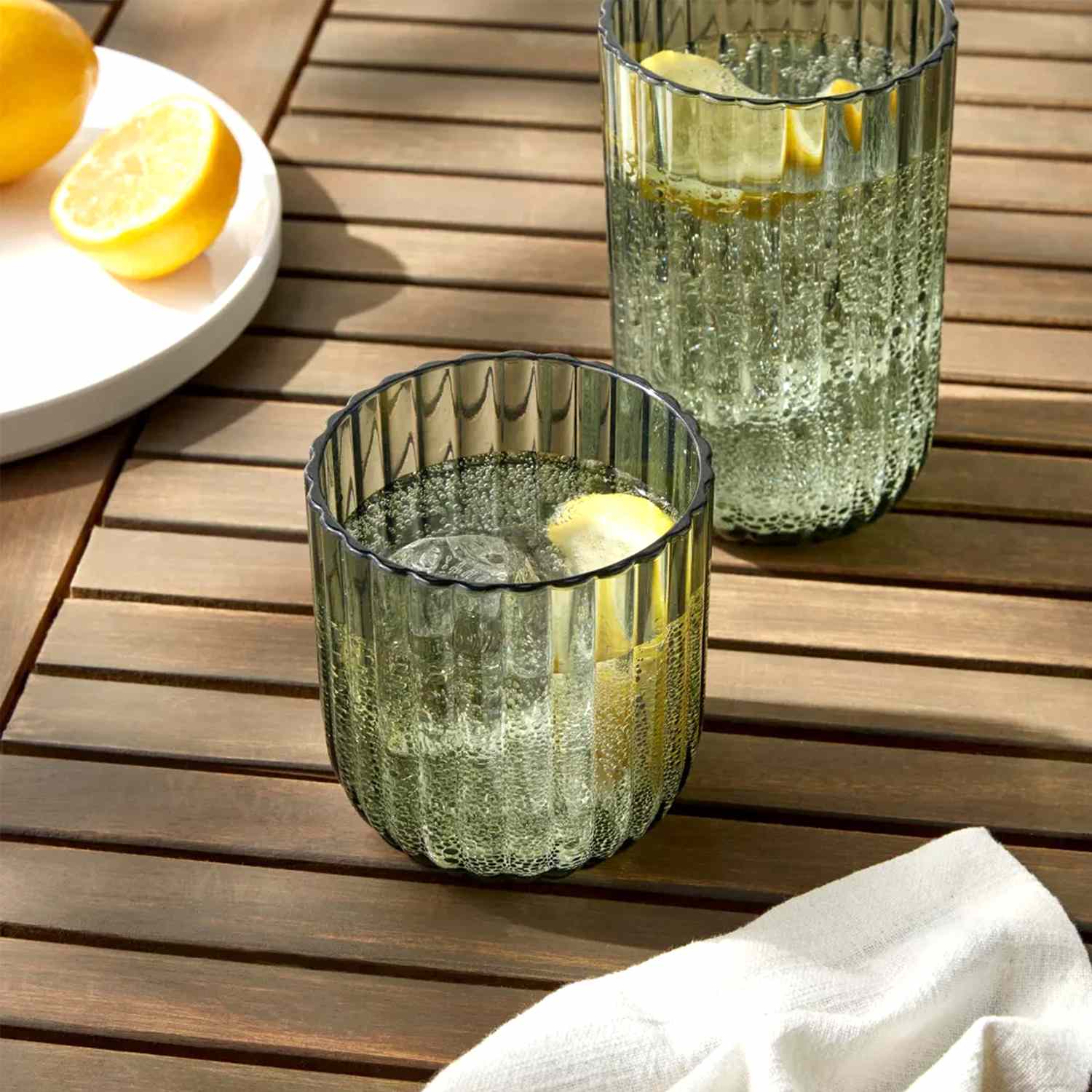 green plastic tumbler on an outdoor table with lemon