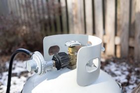 Propane tank with a valve and hose connection in an outdoor setting