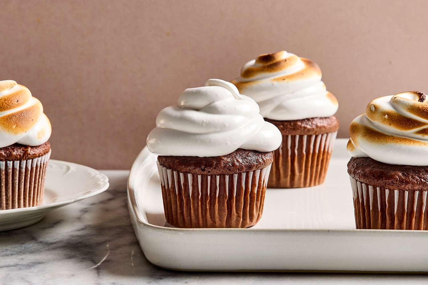Cupcakes with a swirl of marshmallow frosting arranged on a tray