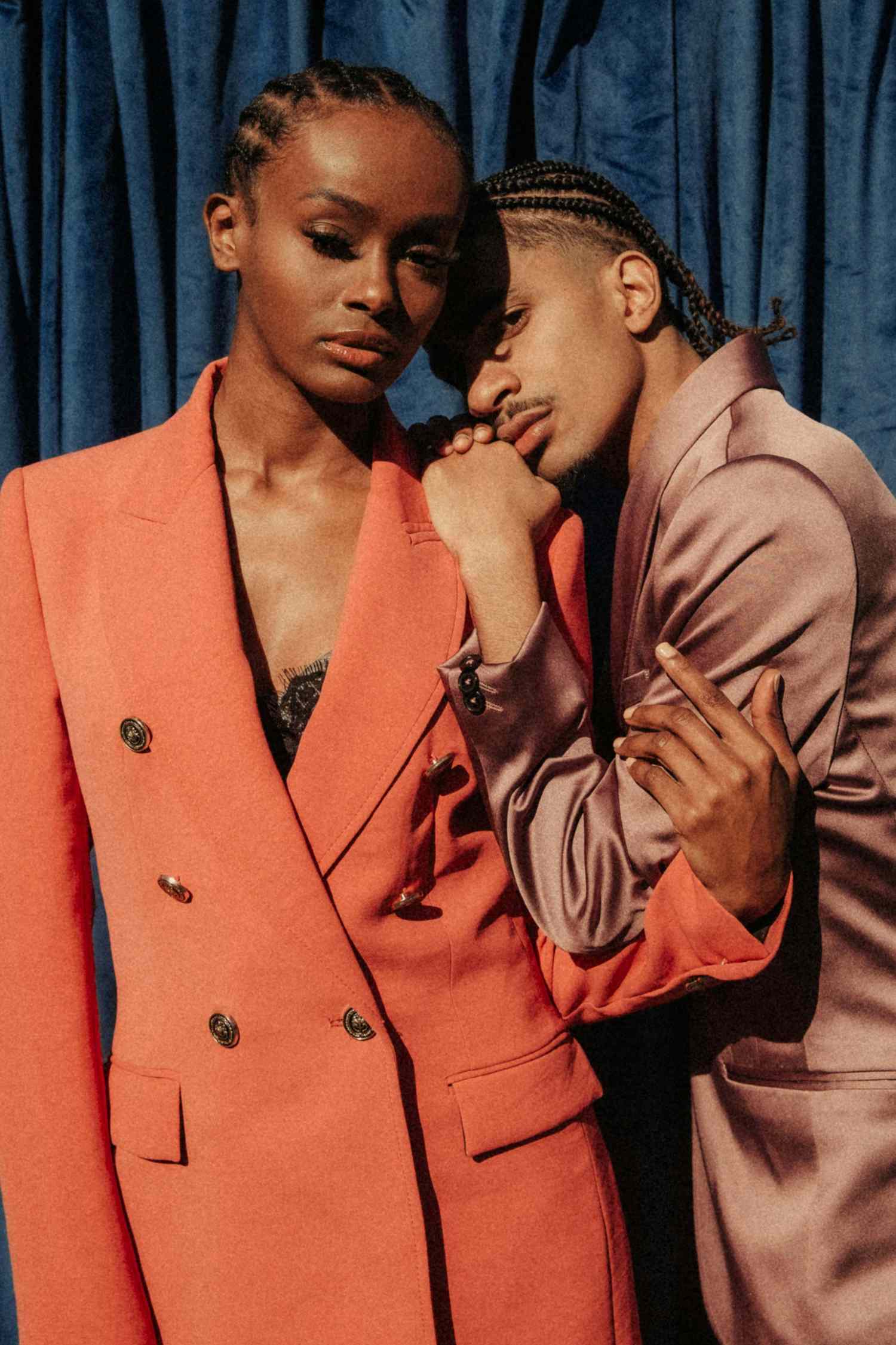 Tahounia Rubel and a companion pose together dressed in formal attire with a cloth backdrop