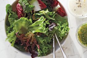 overhead view of bowl of lettuce with dressings on the side