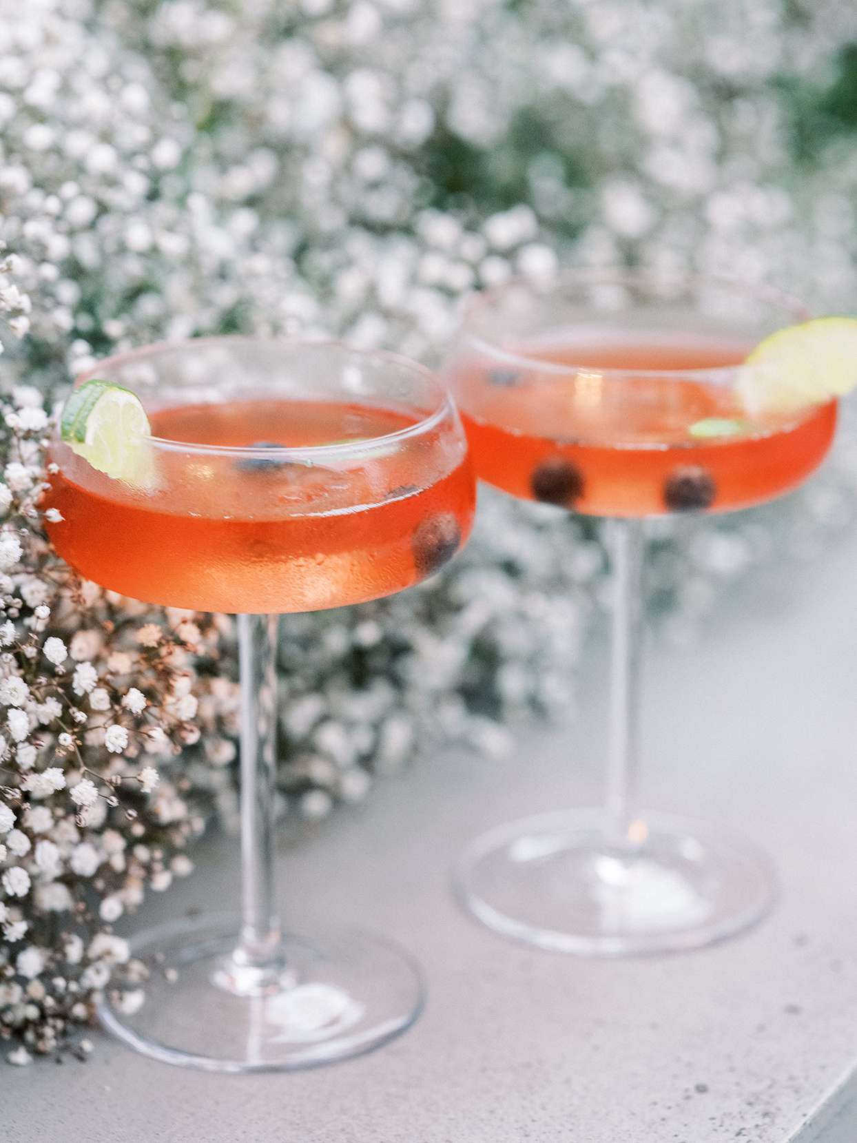 red cocktails with lime wedge on glass edge