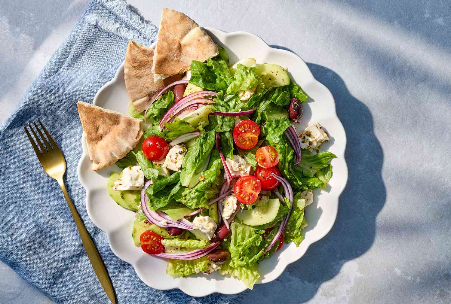 Plate of Greek salad with pita on a blue napkin
