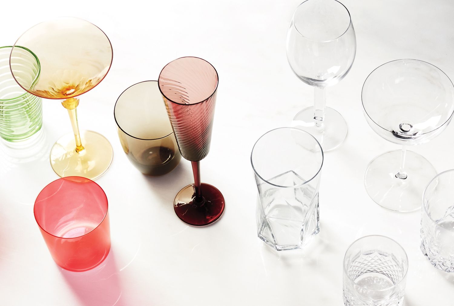 Various glassware items including colored and transparent glasses arranged on a surface