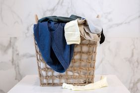 Laundry basket filled with clothes on a marble background
