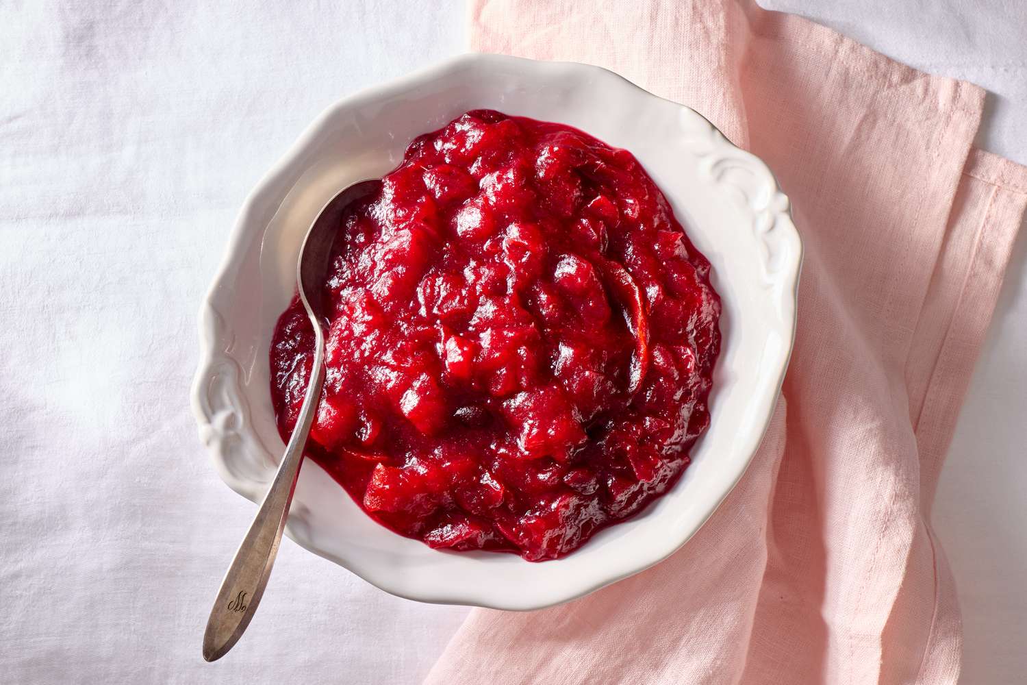 Bowl of cranberry sauce with a spoon on a napkin