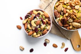 Bowls of various mixed nuts and dried fruits on a white surface