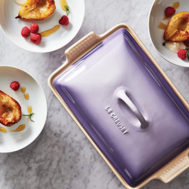 A baking dish with baked pears and plates of dessert