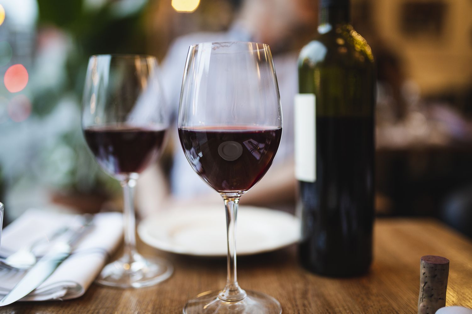 Two glasses of red wine on a table with a wine bottle in a restaurant setting