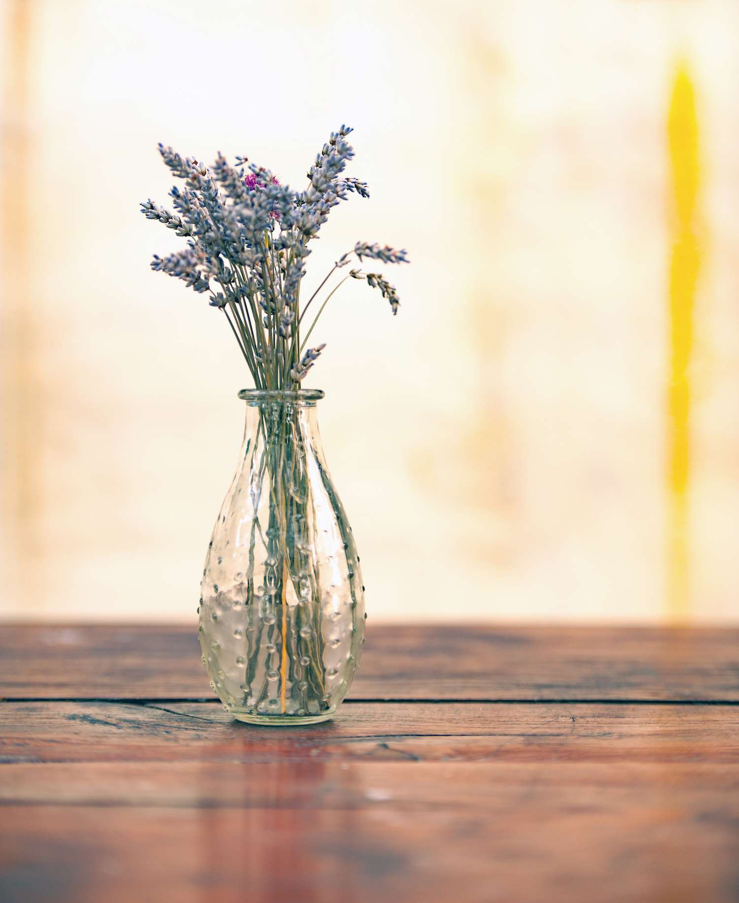 A vase with lavender flowers on a wooden table