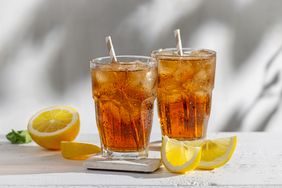 Two glasses of iced tea with lemon wedges on a white surface