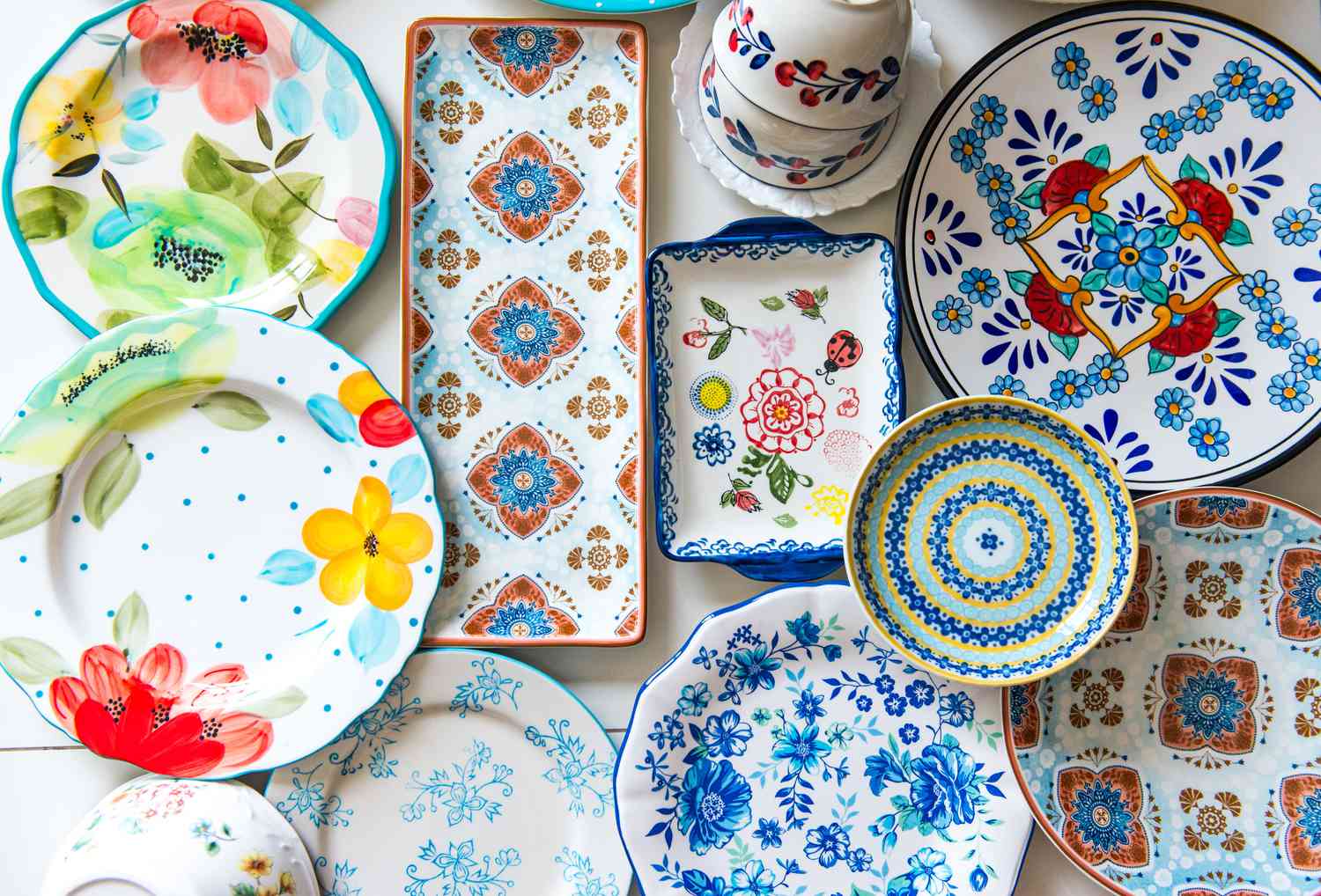 Various designs of colorful ceramic plates arranged flat on the white surface