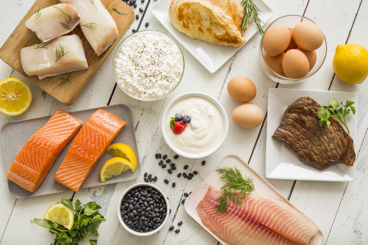 Assorted highprotein foods including fish chicken steak eggs yogurt cottage cheese and beans