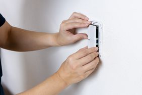 Hands installing or removing a wall-mounted device panel