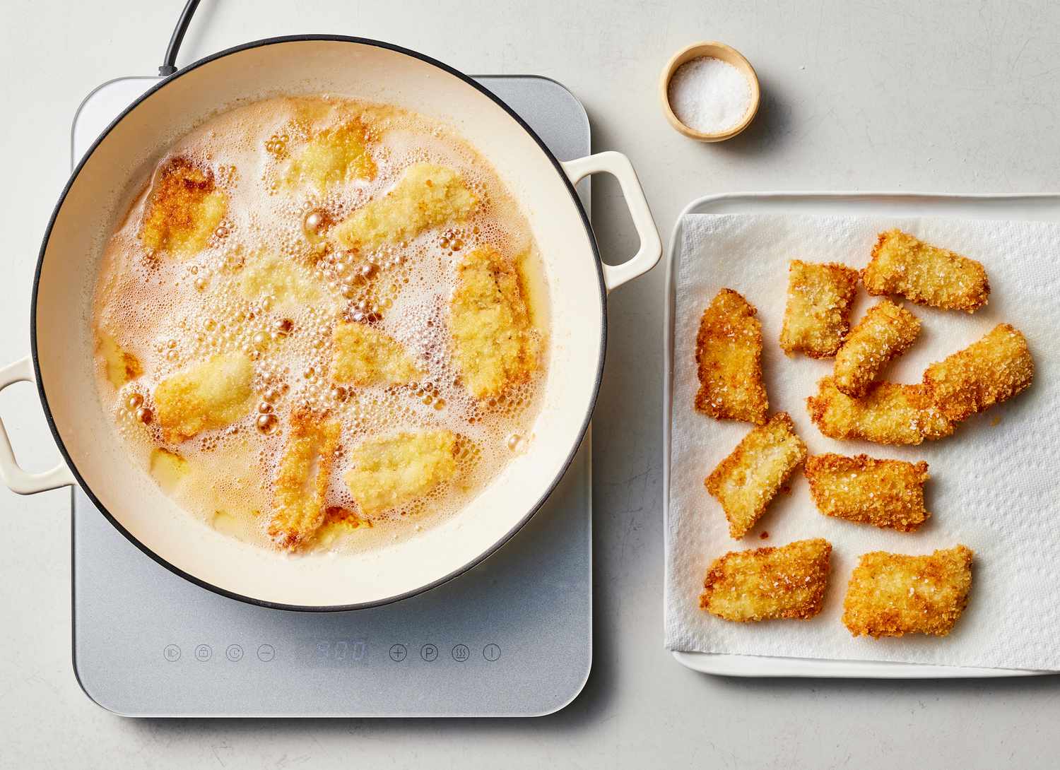 frying breaded fish in oil and drying fish on paper towels