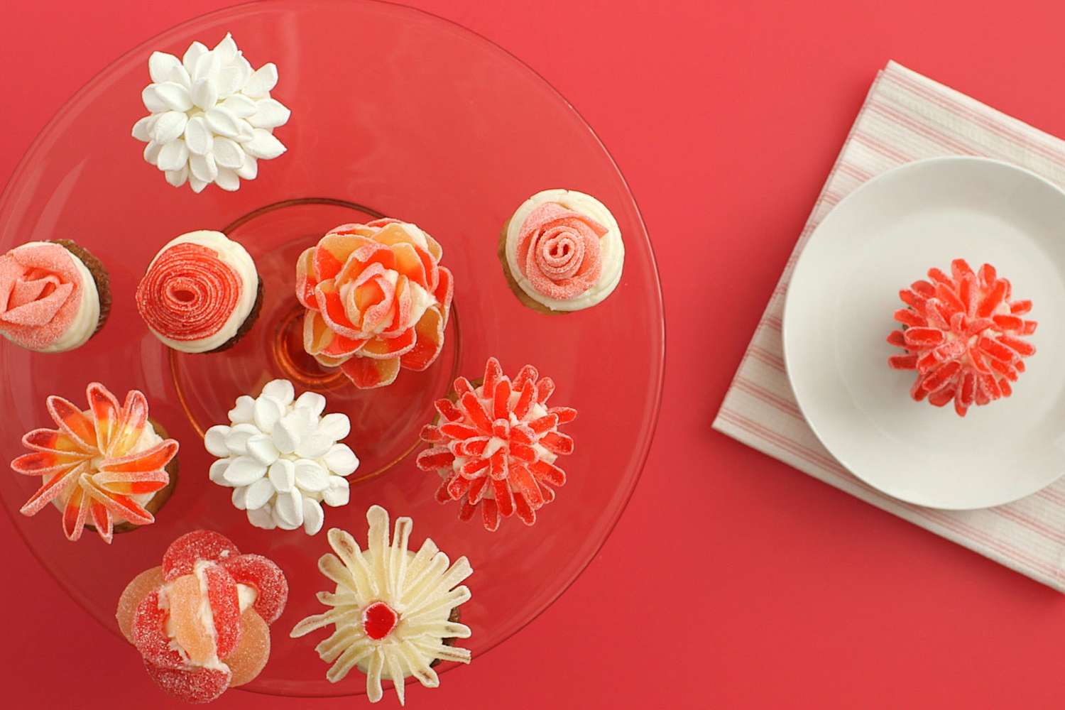 A selection of floralthemed cupcakes displayed on a plate and next to a single cupcake on a separate small dish