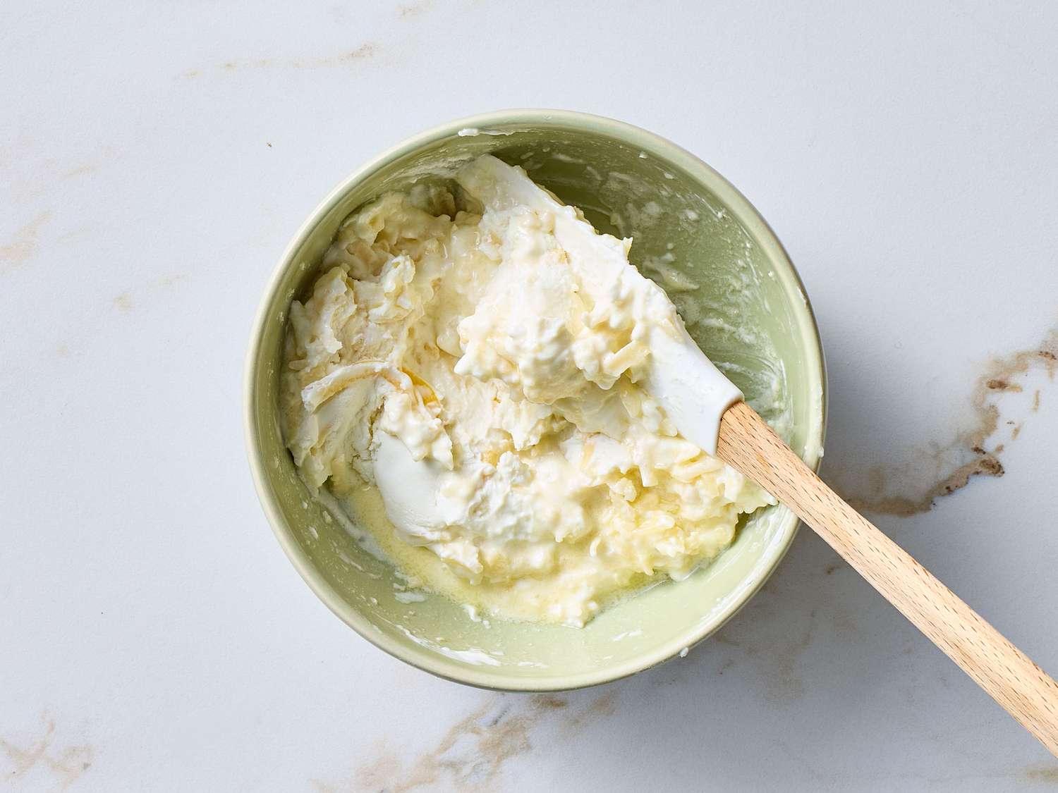 Bowl with a creamy mixture and a spatula on a light surface