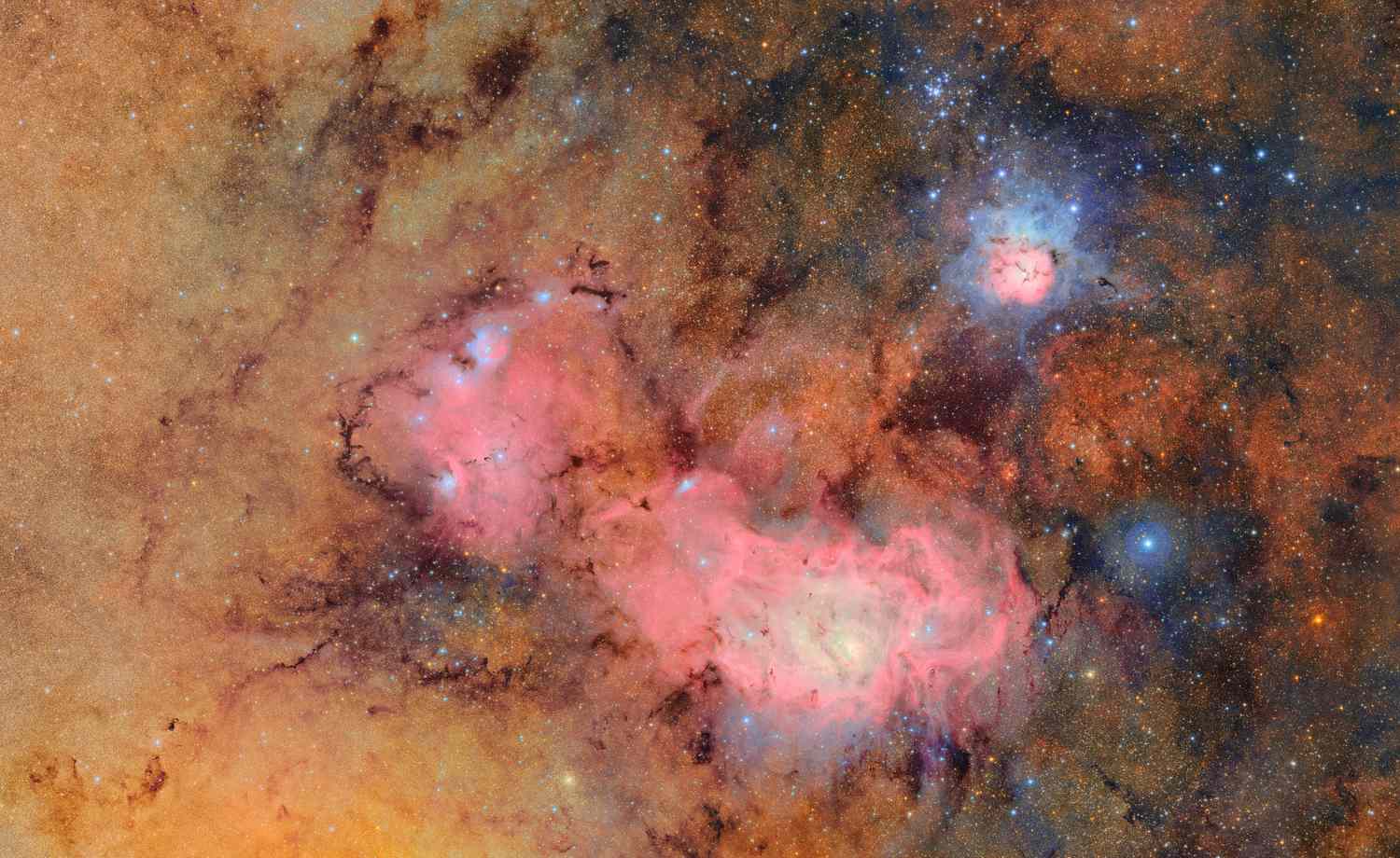 A view of the Trifid Nebula and surrounding region in space, showing detailed interstellar gas and light emissions