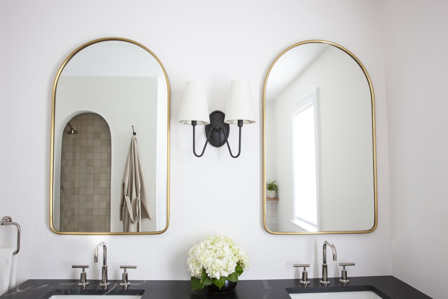 a white bathroom with gold mirrors 