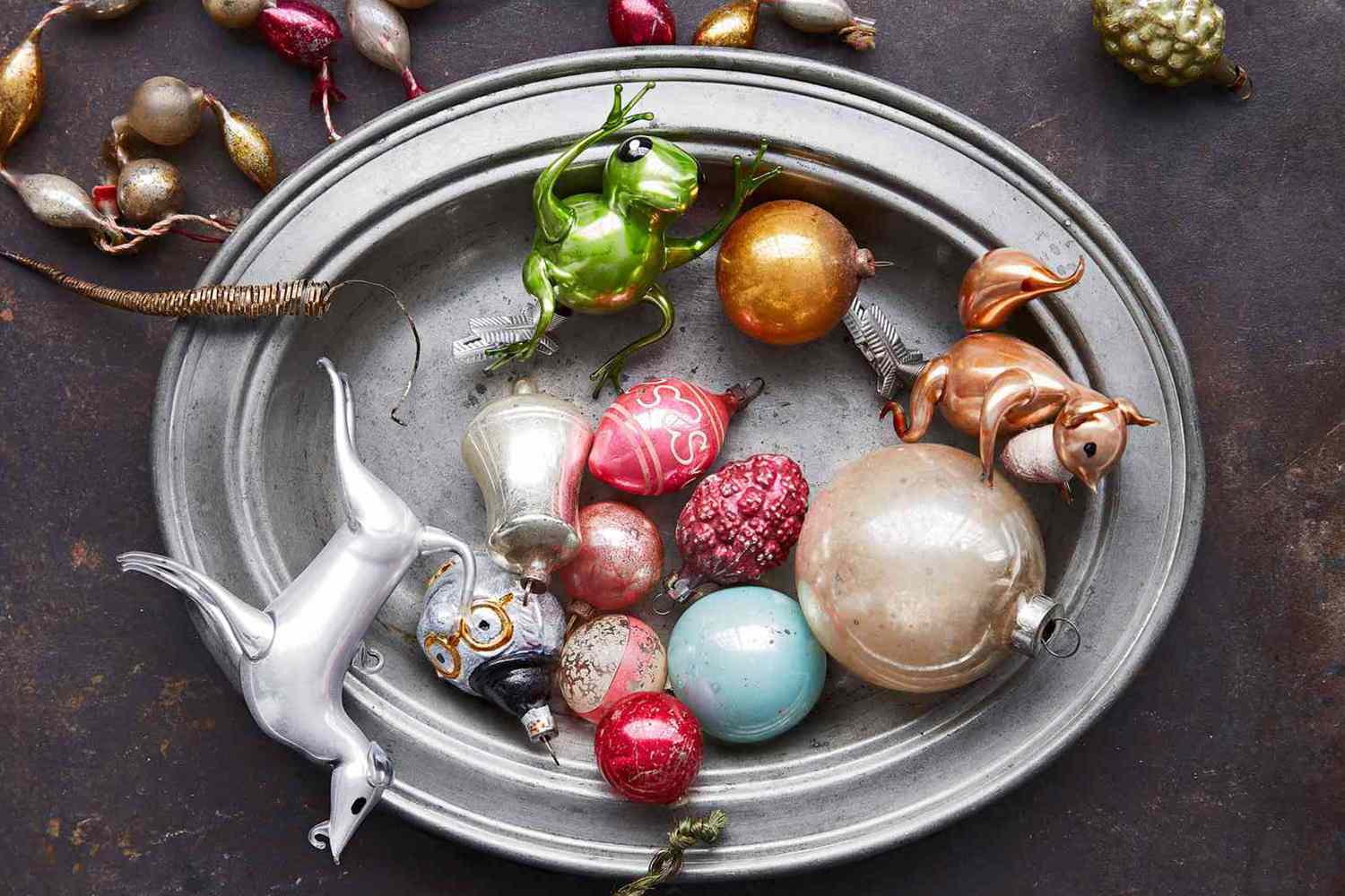 A collection of vintage Christmas ornaments displayed on a metal tray