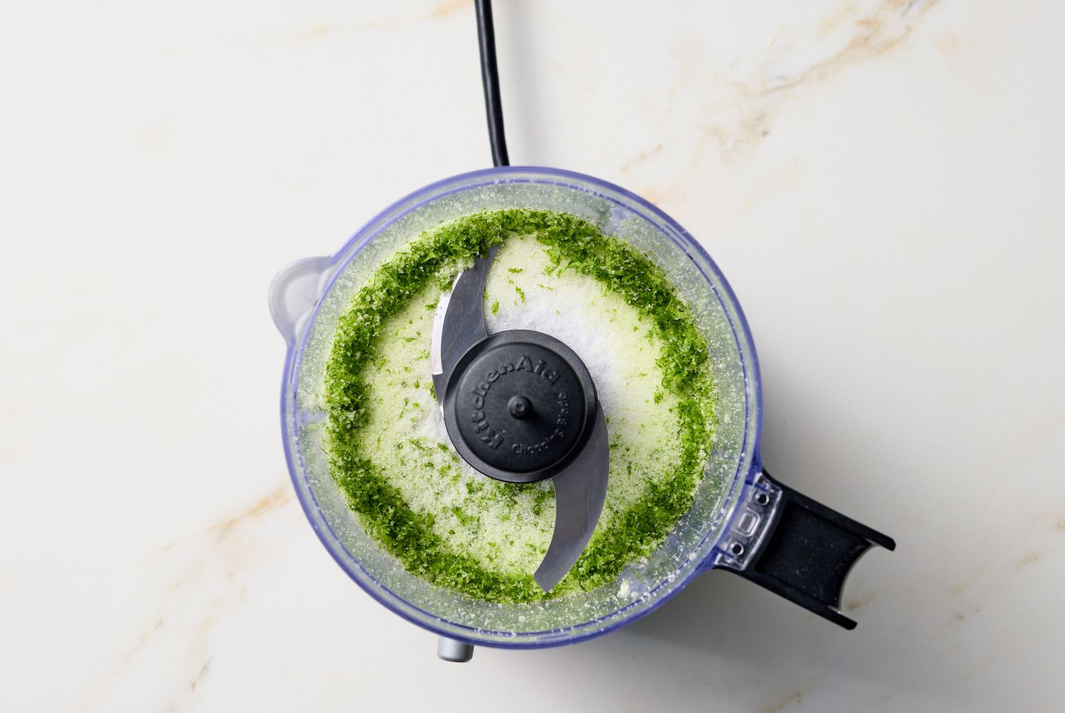 Food processor with green and white mixture inside