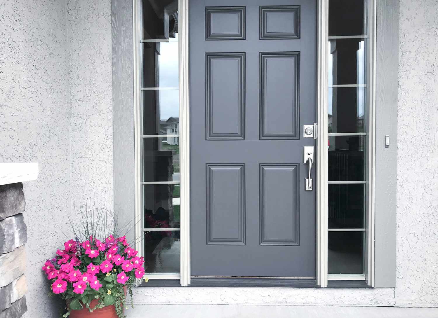 grey front door with pink pot of flowers