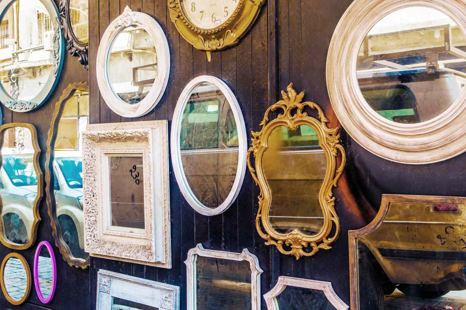 A collection of framed mirrors of various shapes and sizes displayed on a wall