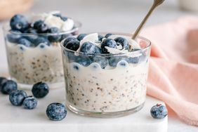 A serving of overnight oats topped with blueberries and a spoon in a glass container
