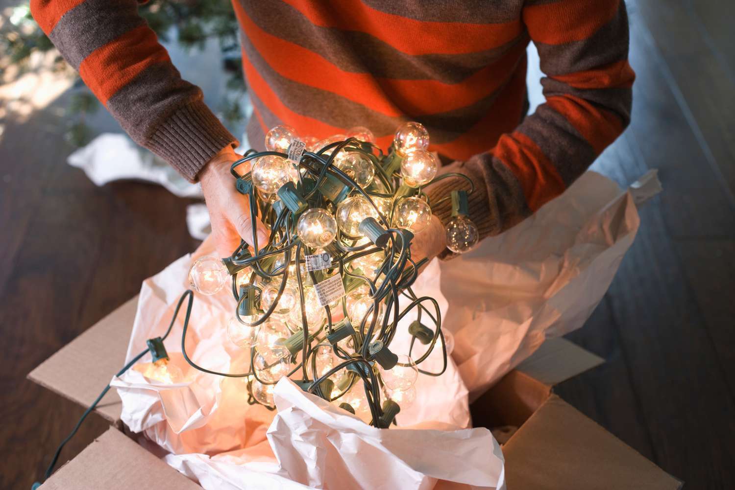 person taking lit Christmas lights out of box