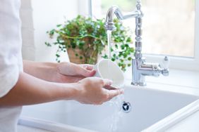 woman hand-washing a mug in sink