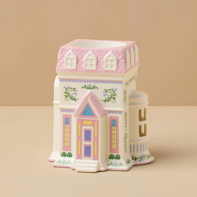 A ceramic container designed like a decorative house with intricate architectural details