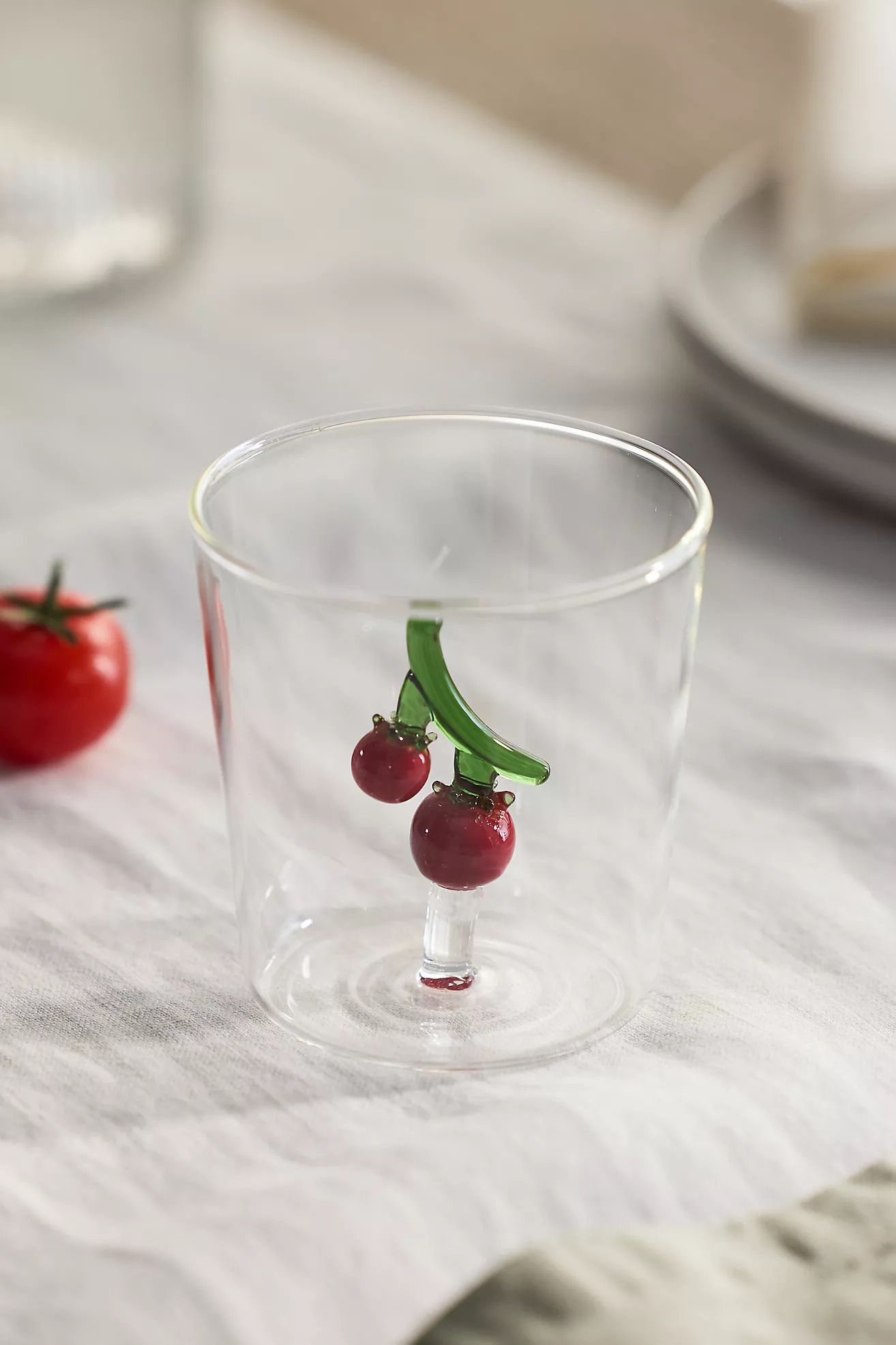 A glass with a tomato design, resting on a surface. 