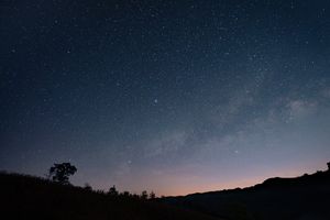 Starfilled night sky above a silhouette of hills and trees a serene astronomical view