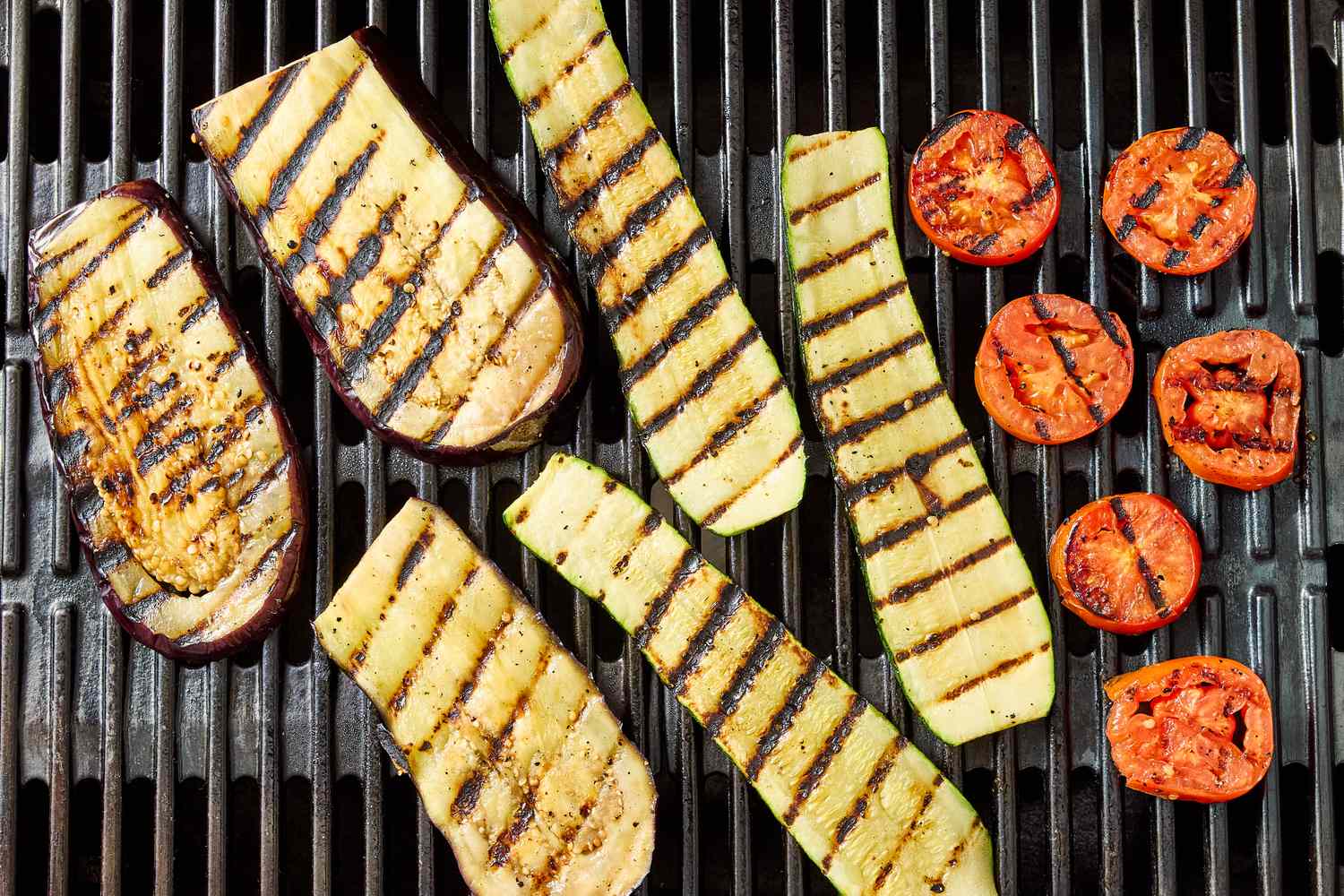 Grilled slices of eggplant zucchini and tomato on a grill